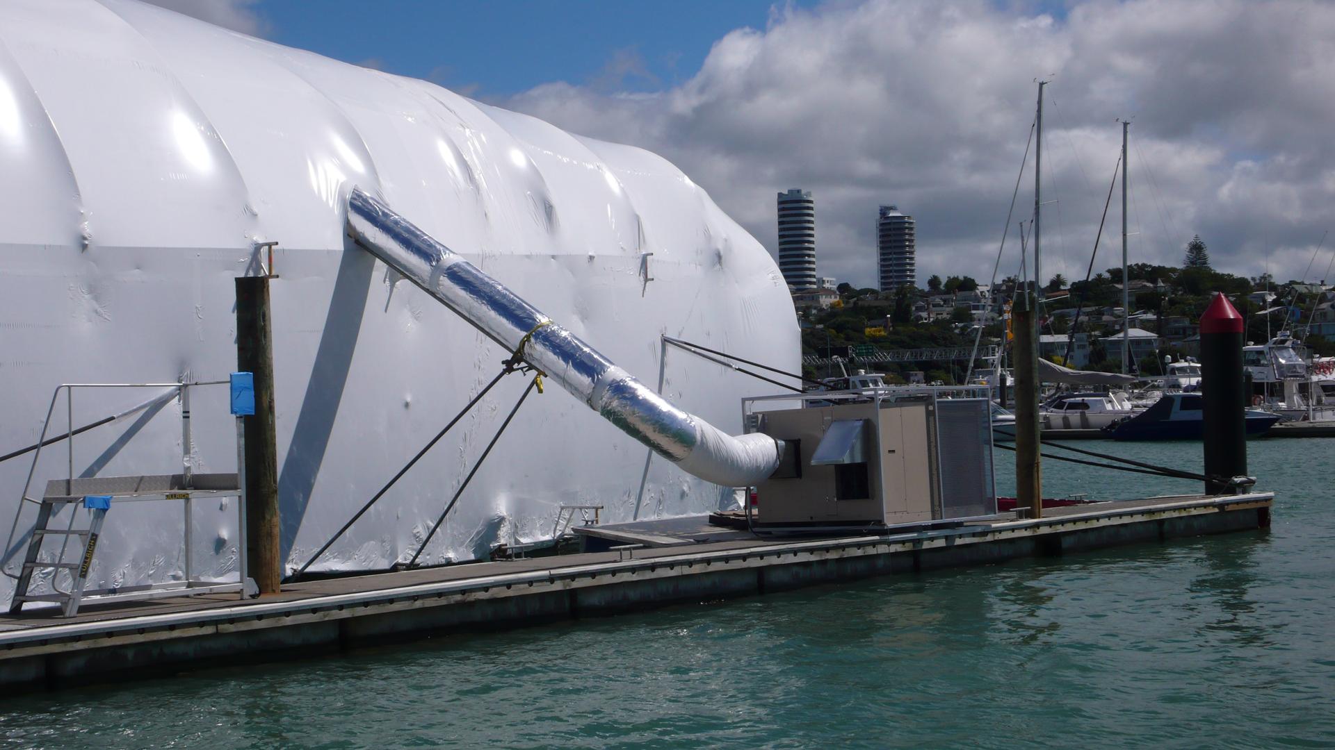 A Temperzone air conditioning unit on a marina pontoon, ducted into a large shrink-wrapped enclosure